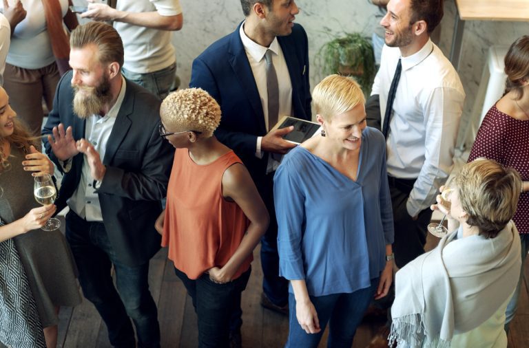 Diverse group of people engaging in conversation at a casual corporate networking event in Seattle, some holding drinks.