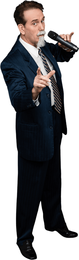 A corporate entertainer in Seattle, dressed in a blue suit and striped tie, speaking into a microphone while pointing with his right hand.