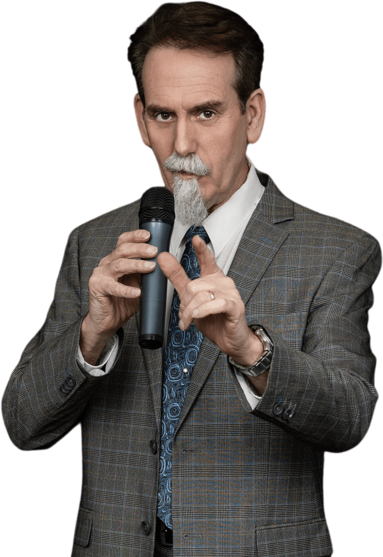 Seattle corporate entertainer in a gray suit and blue paisley tie holding a microphone and pointing forward, with a serious expression.